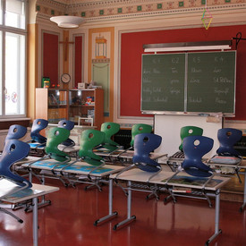 Klassenzimmer mit hochgestellten Stühlen und Schiefertafel